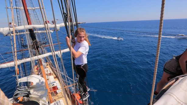 Photo of a high school student climbing the rigging of a tall ship